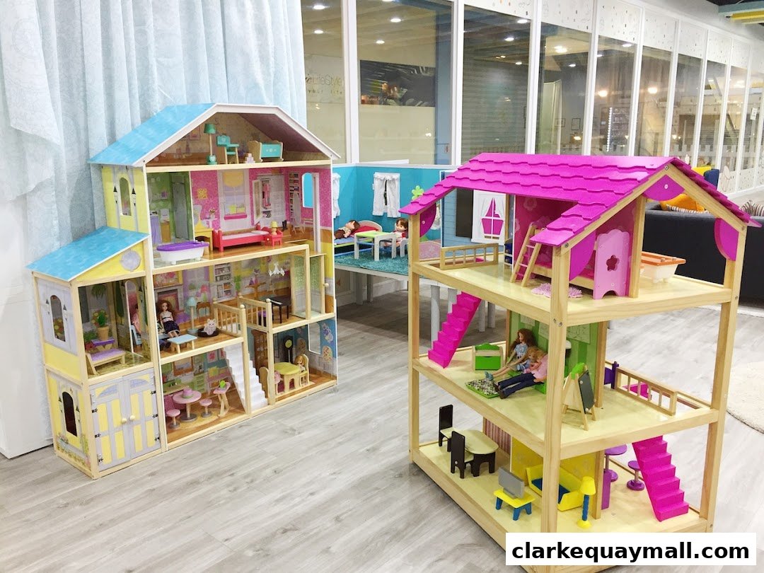 Two detailed dollhouses with furniture and dolls are displayed on a wooden floor.