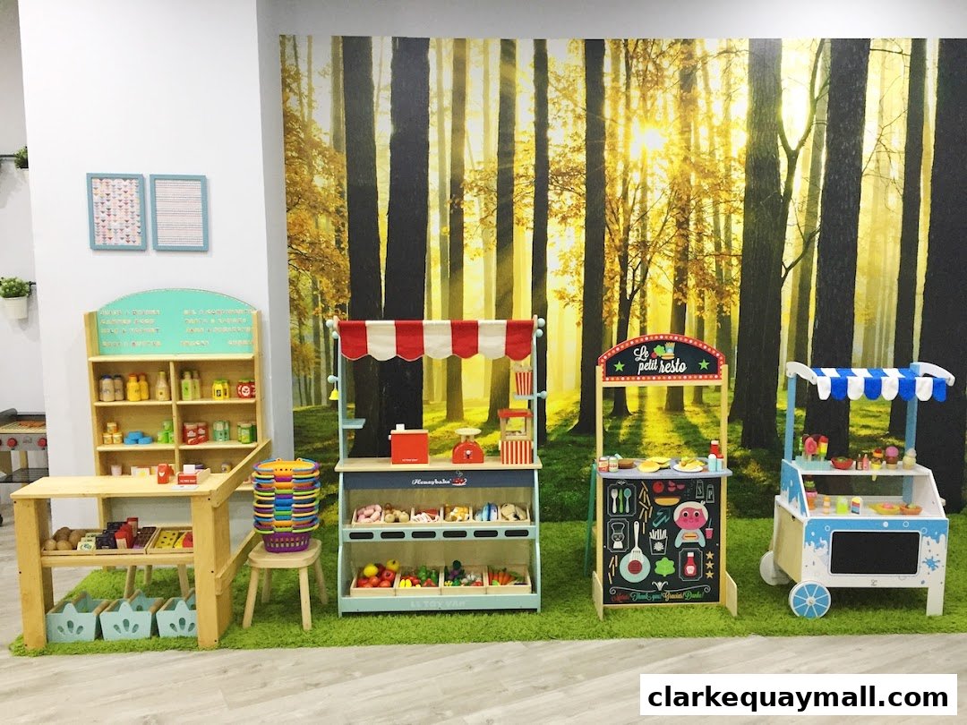Play food stalls and shelves stocked with toy groceries, set against a forest backdrop.