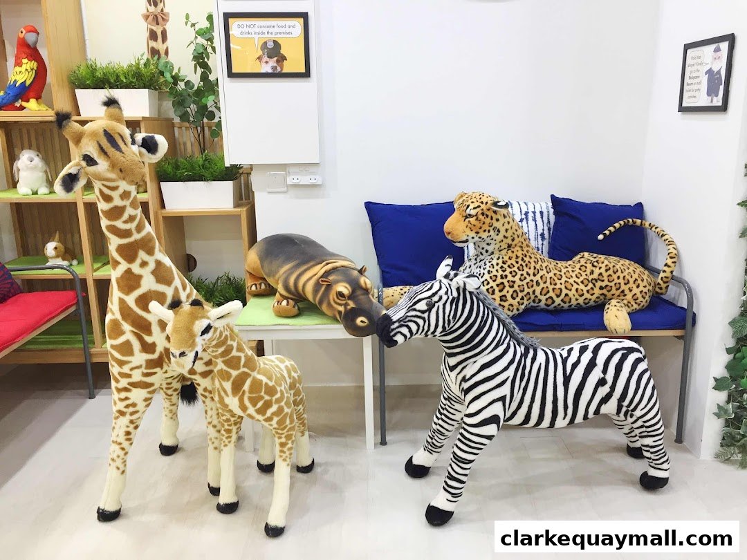 A collection of large, plush safari animals including giraffes, a zebra, a leopard, and a hippo.