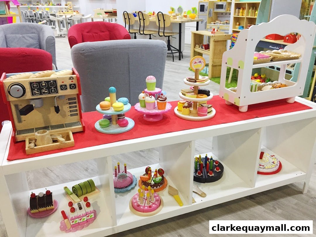 A display of wooden toy food items, including a coffee machine, cakes, and pastries.