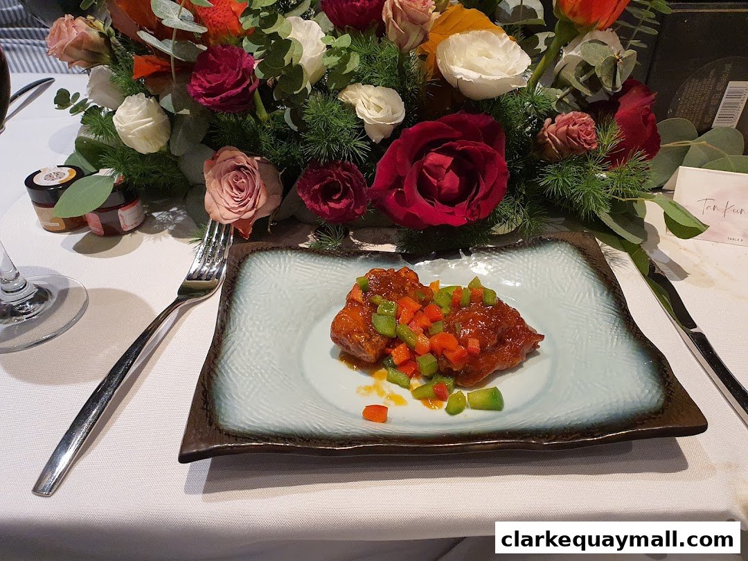 A plate of food with diced vegetables sits on a table with a floral centerpiece.