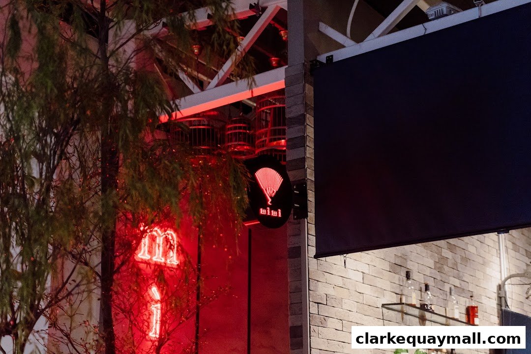 The Riverhouse Singapore storefront at night with neon signs and a dark awning.