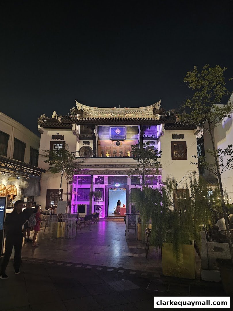 The Riverhouse Singapore at night, featuring traditional architecture and outdoor seating.