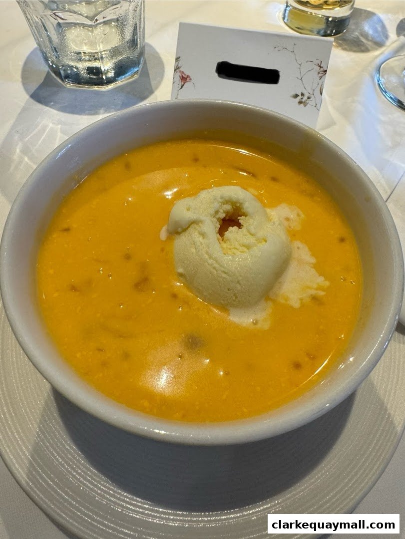A bowl of creamy orange soup topped with a scoop of ice cream.