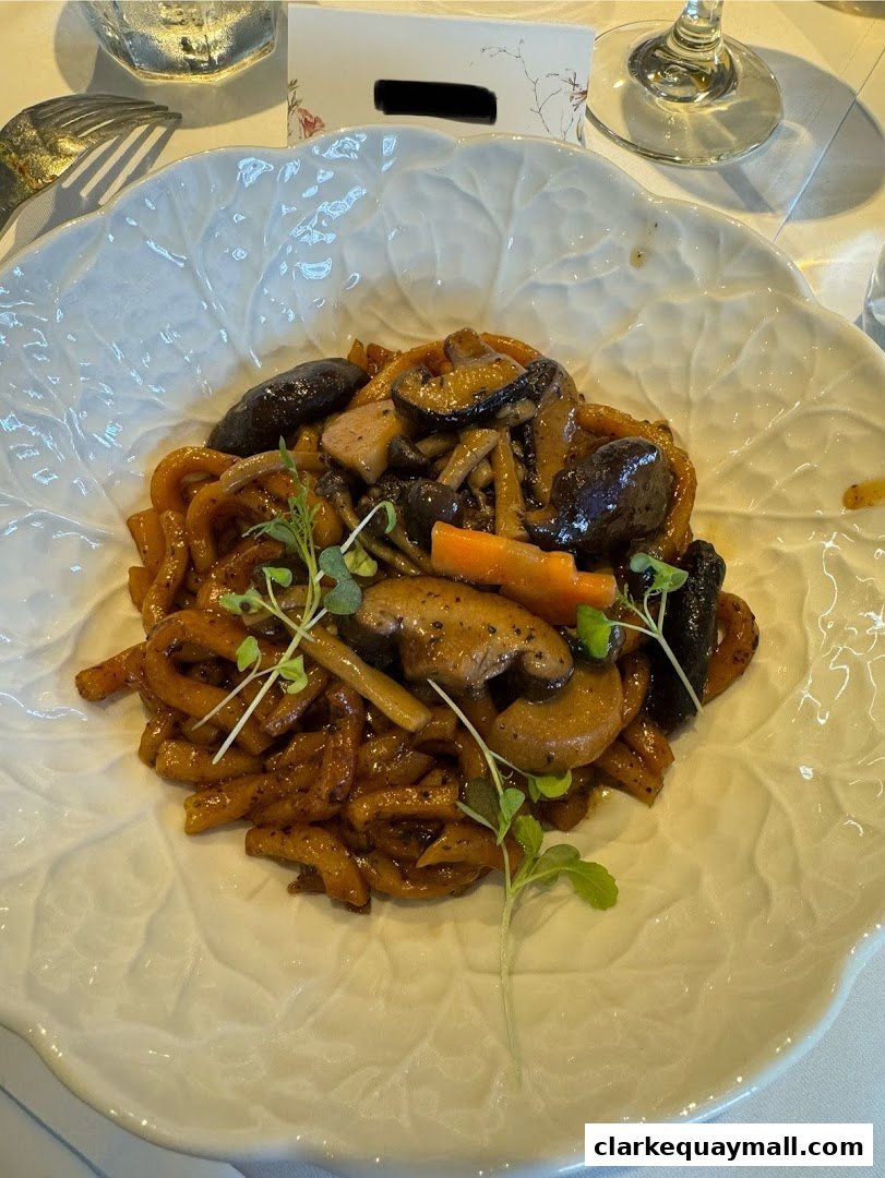 A close-up of a delicious noodle dish with mushrooms and carrots served in a leaf-shaped bowl.