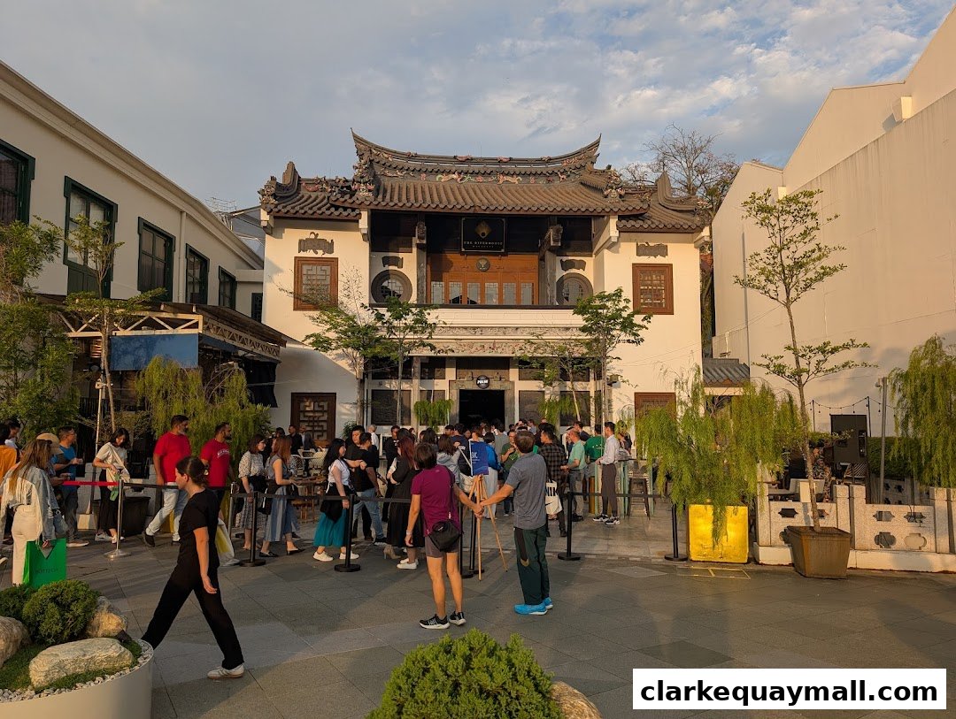 A crowd gathers outside The Riverhouse Singapore, a building with traditional East Asian architecture.