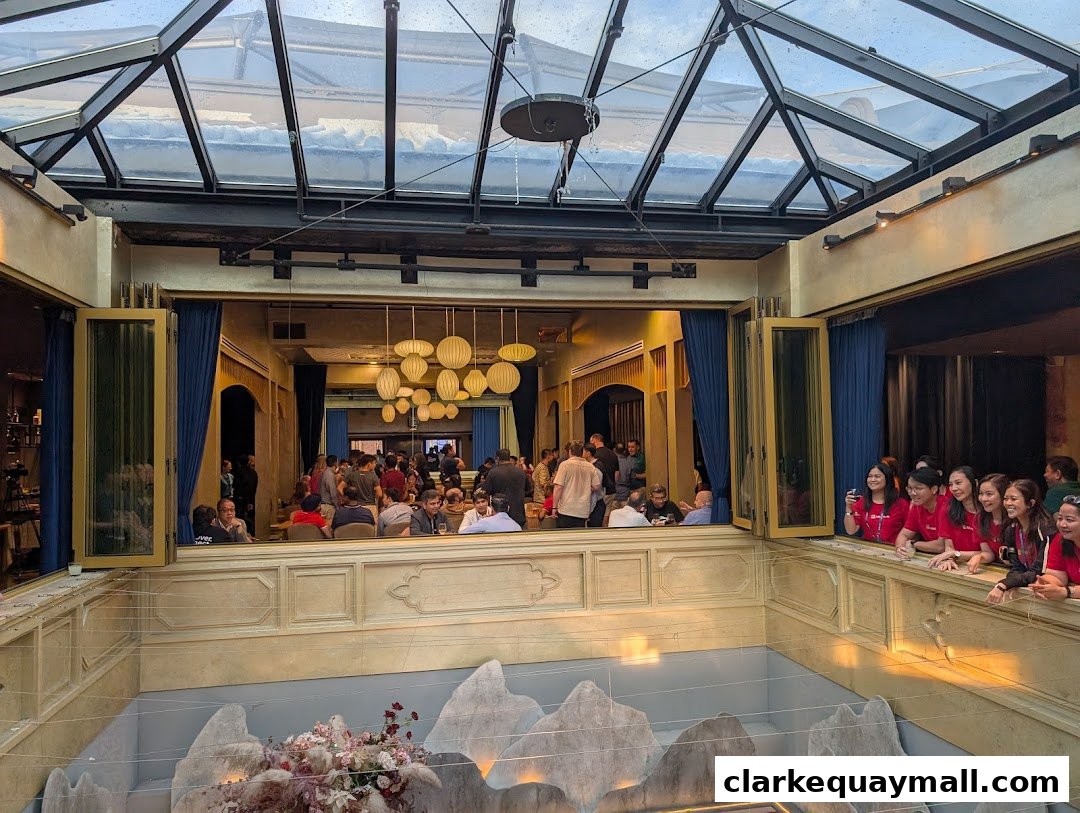 Interior view of a restaurant with a glass ceiling, people dining, and a decorative floral display.