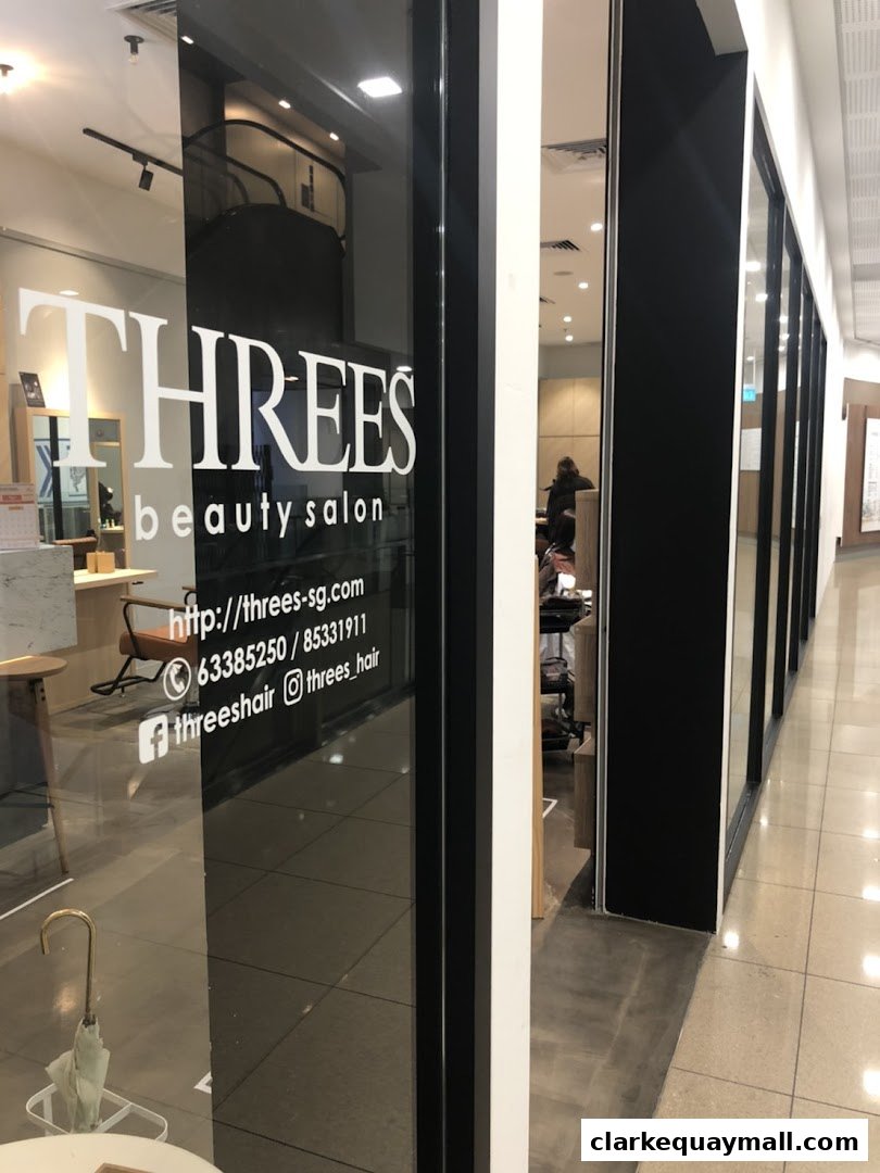 The entrance of THREES Beauty Salon, featuring its logo and contact information on the glass door.