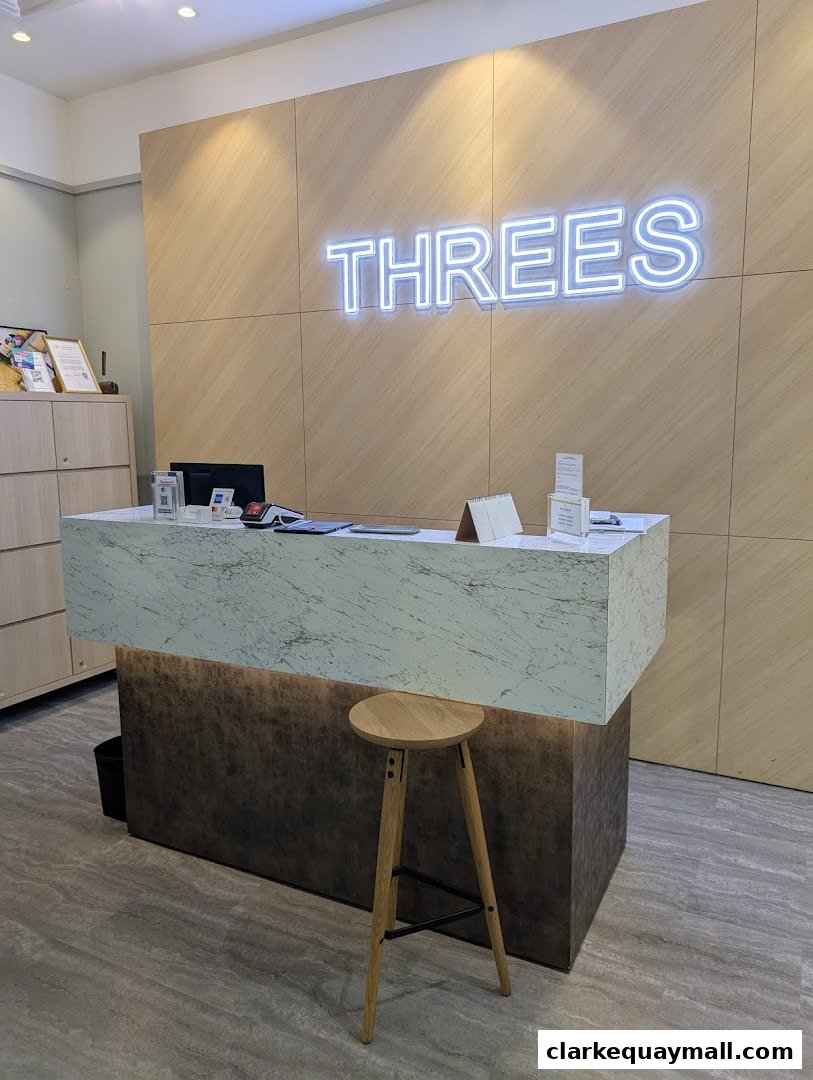 The reception area of THREES Beauty Salon features a modern counter with a neon sign.