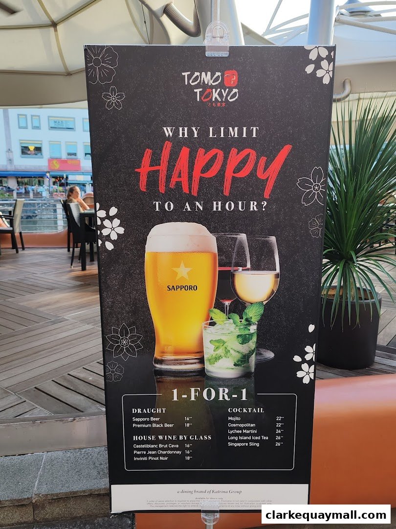 A promotional sign for Tomo Tokyo offering a 1-for-1 happy hour deal on drinks.