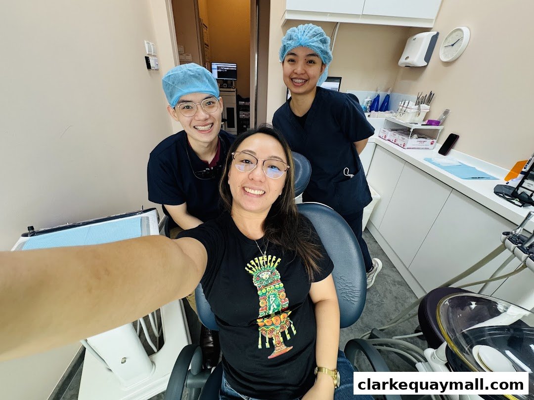 A patient smiles with two dental professionals in a clean, modern dental clinic.