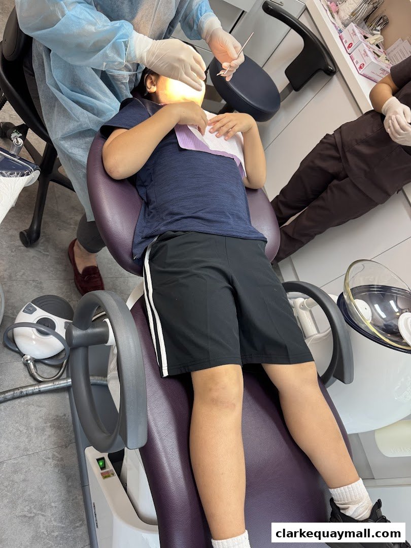 A child sits in a dental chair while a dentist examines their teeth.