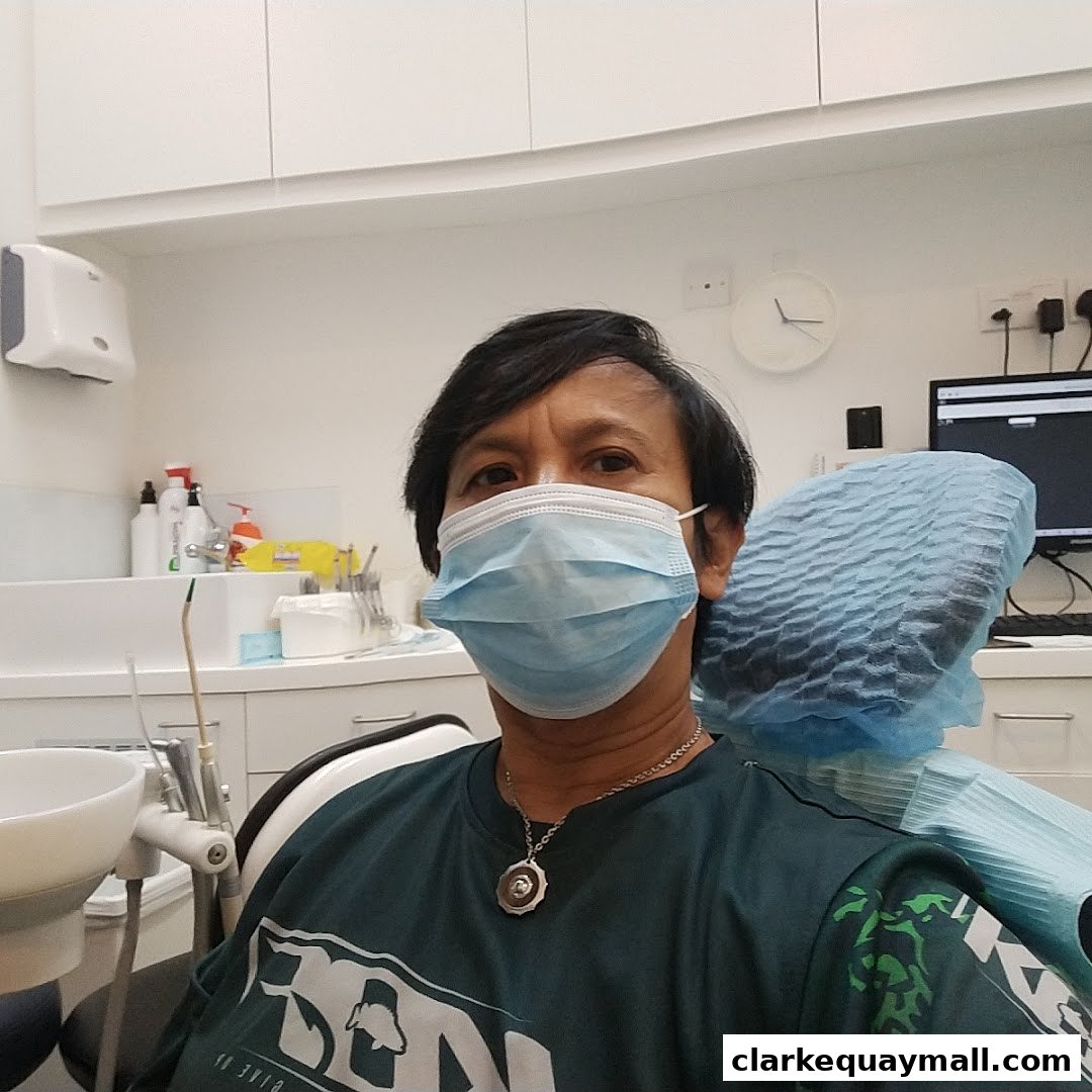 A person wearing a mask and dental cap sits in a dental chair, ready for a dental appointment.