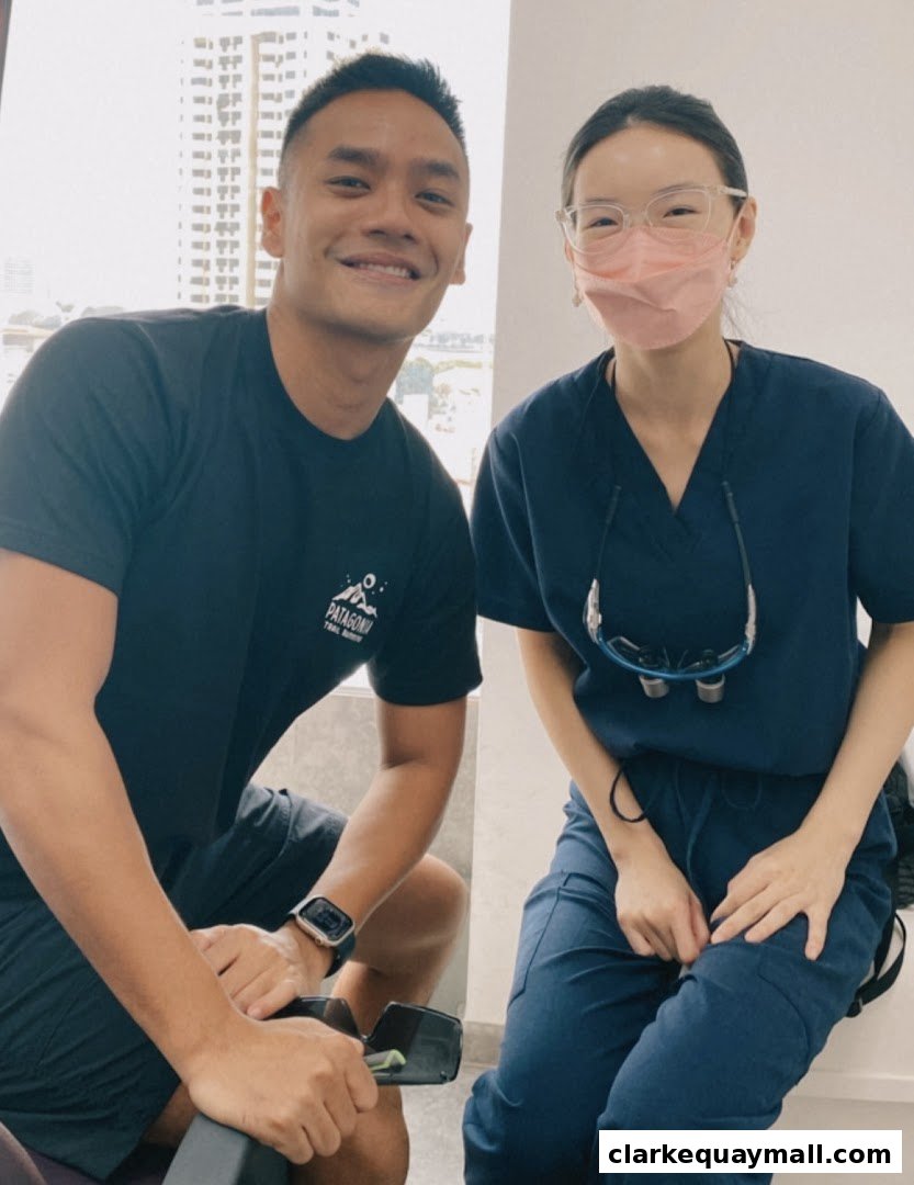 A man and a woman, likely a dentist, smiling at the camera in a bright room.