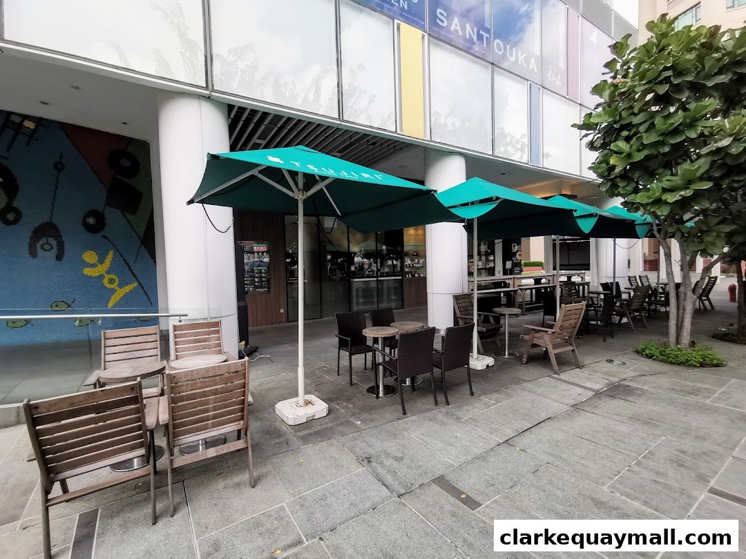 Outdoor seating area with tables and chairs under green umbrellas at TSUJIRI The Central Store.