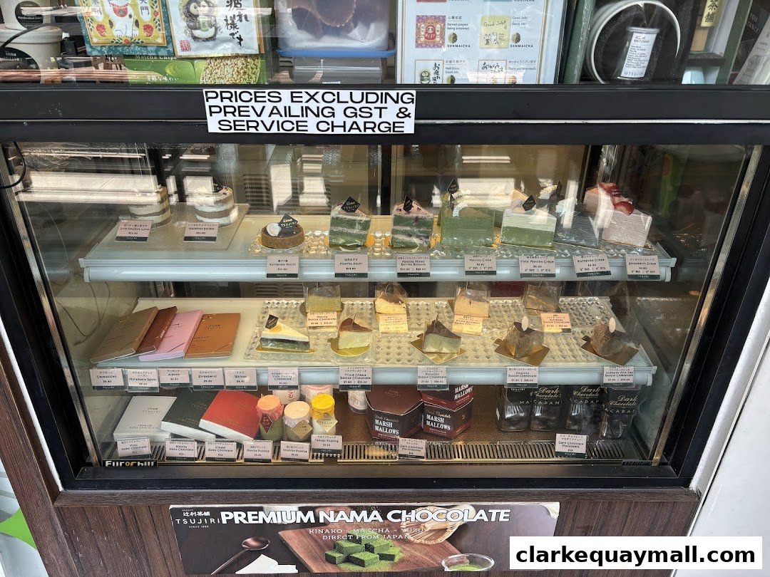 A display case filled with various cakes, pastries, and chocolates from TSUJIRI.
