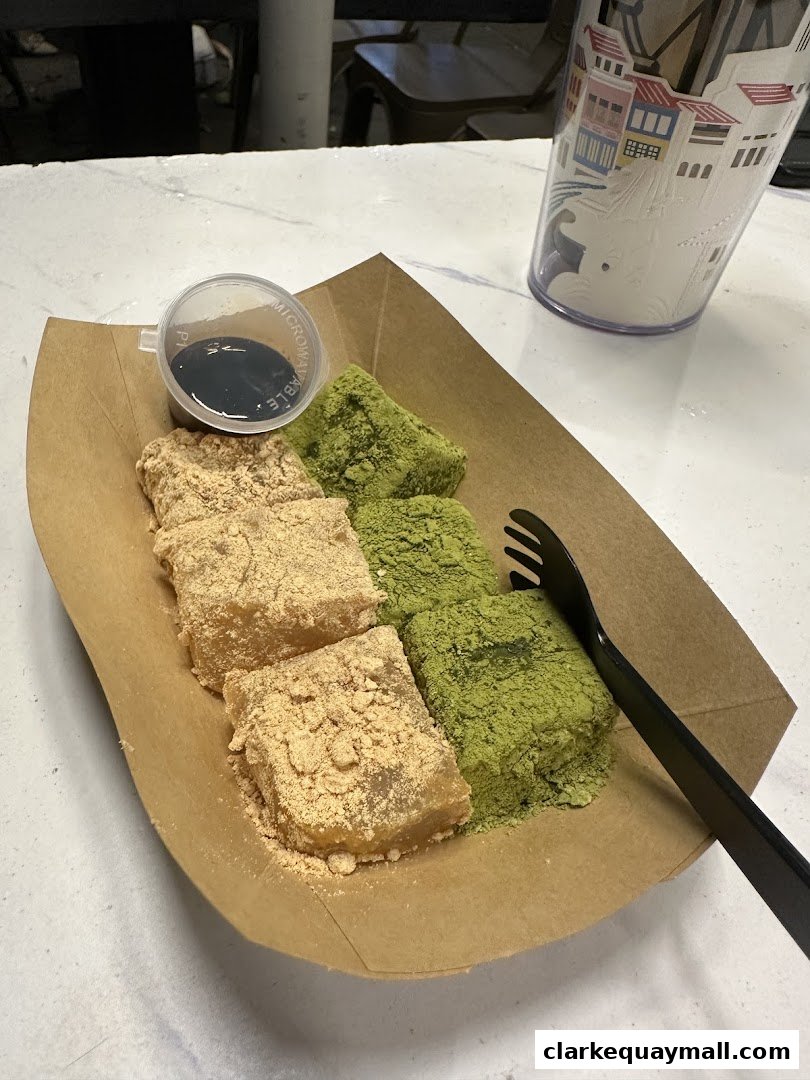 A serving of mochi dusted with kinako and matcha, with a side of dipping sauce.