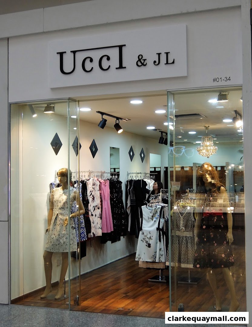 A boutique clothing store called Ucci & JL with mannequins displaying dresses in the window.