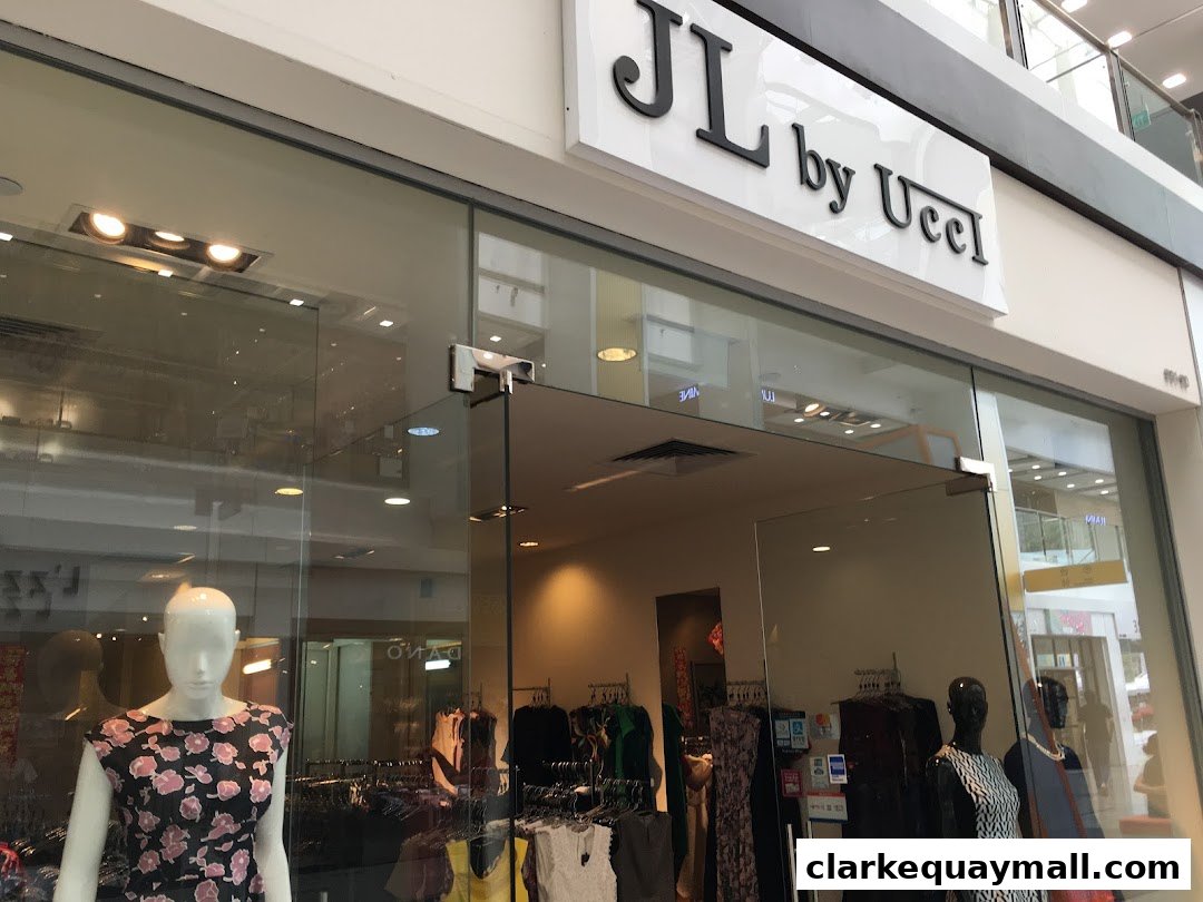 The entrance of a clothing store named JL by Ucci, featuring mannequins and clothing racks.