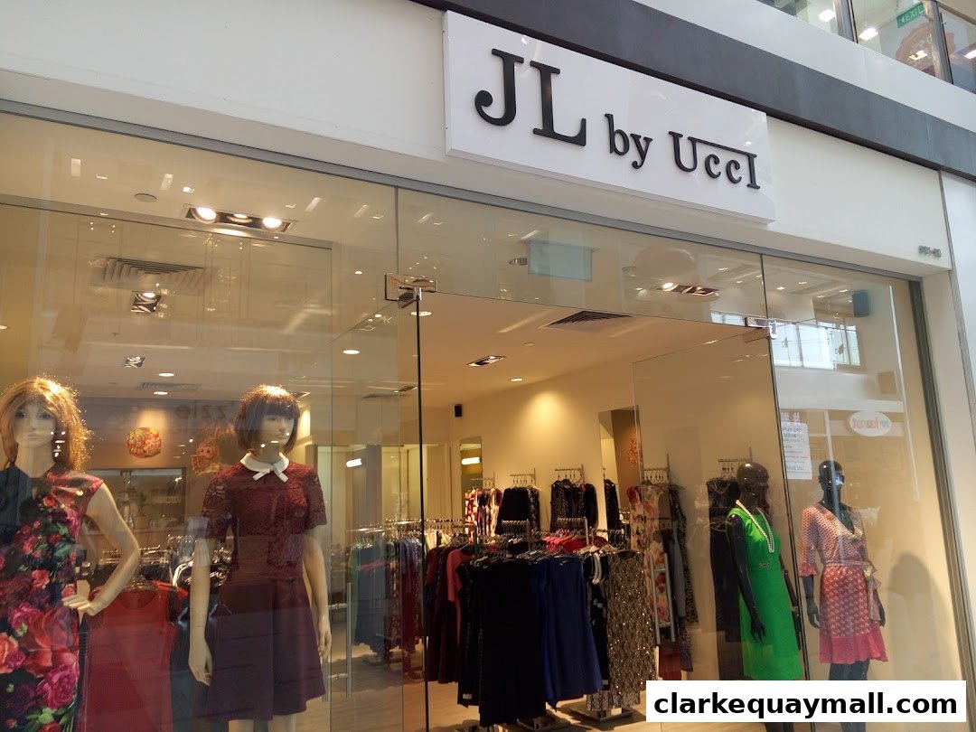The exterior of a fashion boutique named JL by Ucci, showcasing mannequins and clothing displays.