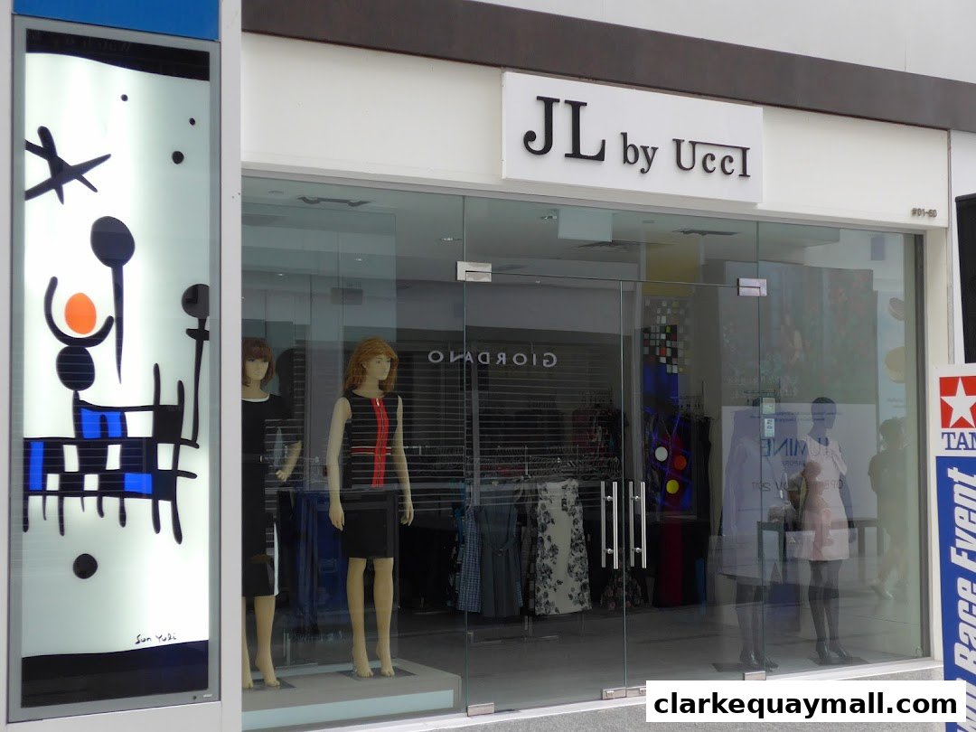 The storefront of a clothing boutique named JL by Ucci, featuring mannequins and artwork in the window.