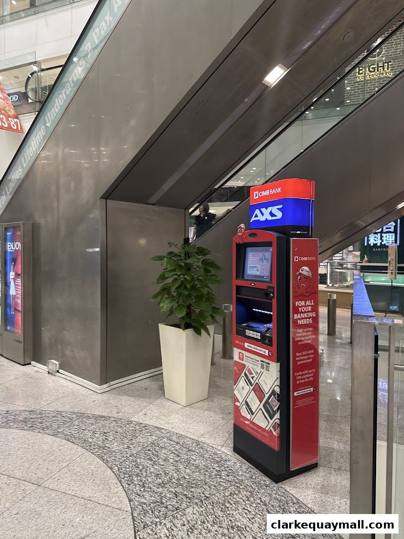 A CIMB Bank AXS machine is located next to an escalator in a shopping mall.
