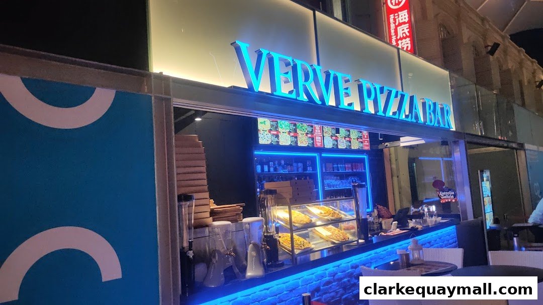 The Verve Pizza Bar storefront at night, featuring bright neon signage and illuminated displays.