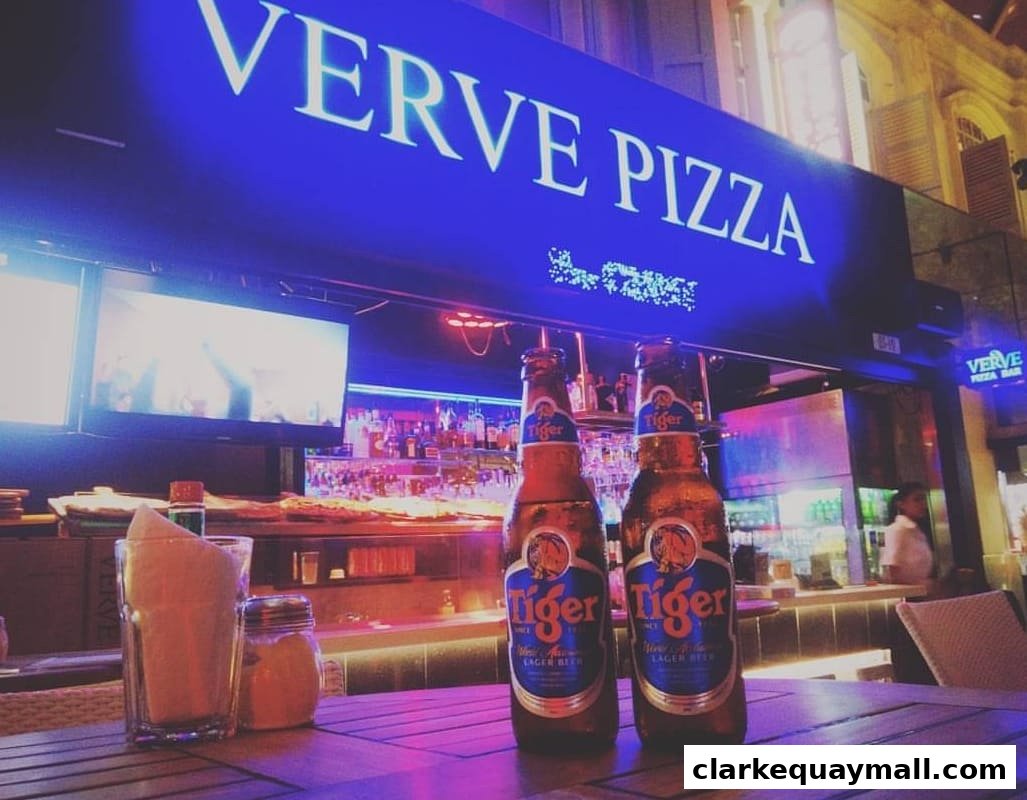 Two bottles of Tiger beer on a table in front of Verve Pizza Bar with neon lighting.