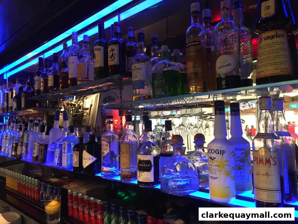A well-stocked bar with shelves of liquor bottles illuminated by blue LED lights.