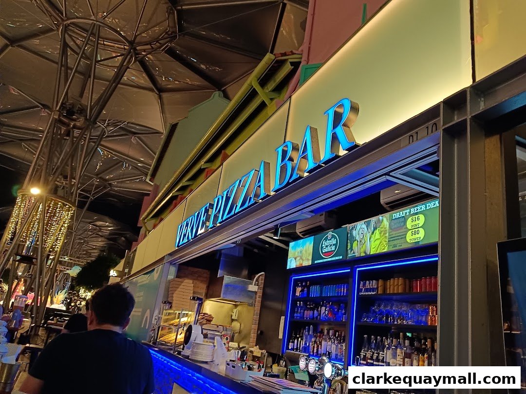 The Verve Pizza Bar storefront at night with neon signage and a well-stocked bar.