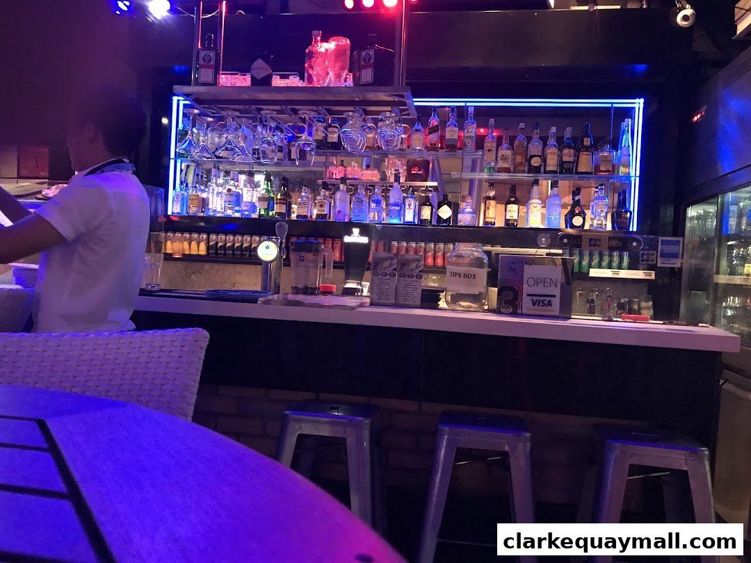 A bartender prepares drinks behind a well-stocked bar with bottles and glassware.