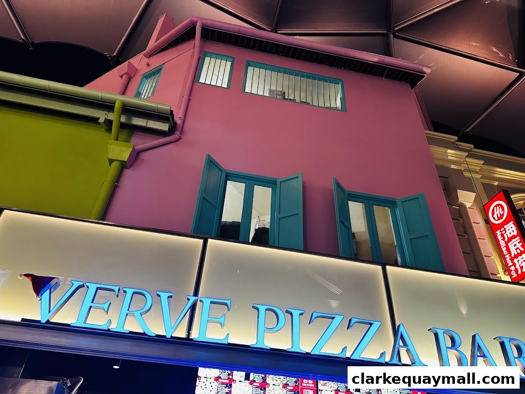 The exterior of Verve Pizza Bar with colorful buildings and neon signage.