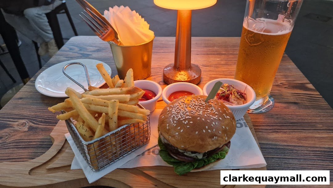 A juicy burger, crispy fries, and a cold beer served on a wooden table.