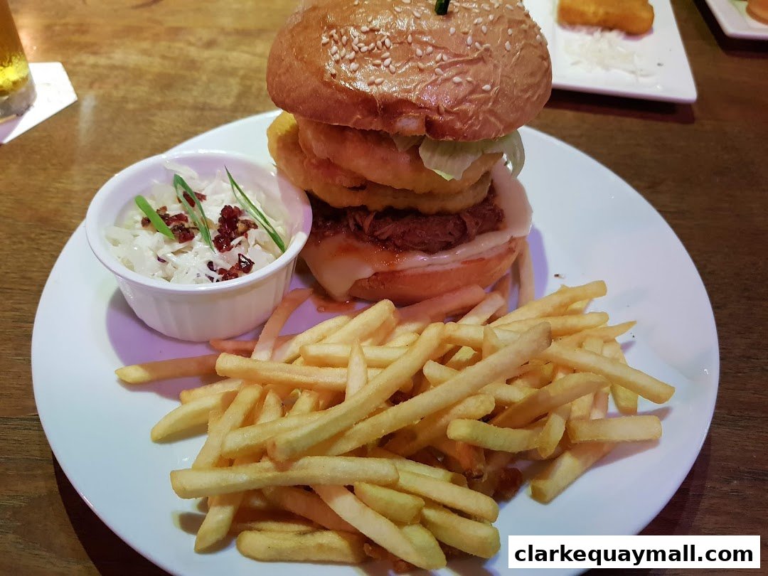 A juicy burger with fries and coleslaw served on a white plate.