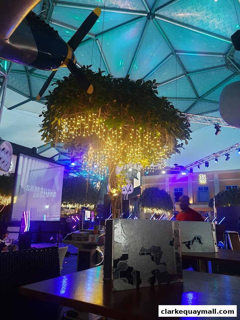 An indoor/outdoor dining area with decorative lights, a tree, and a projected screen.