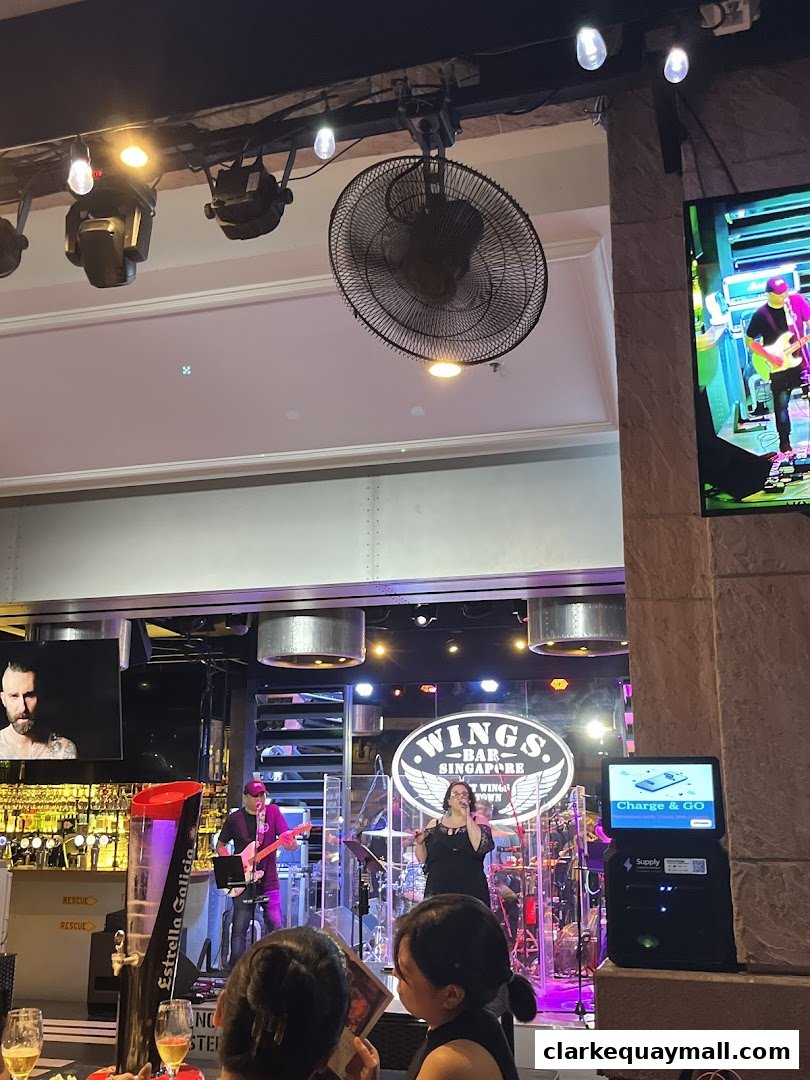 A live band performs on stage at Wings Bar & Grill, with patrons watching.
