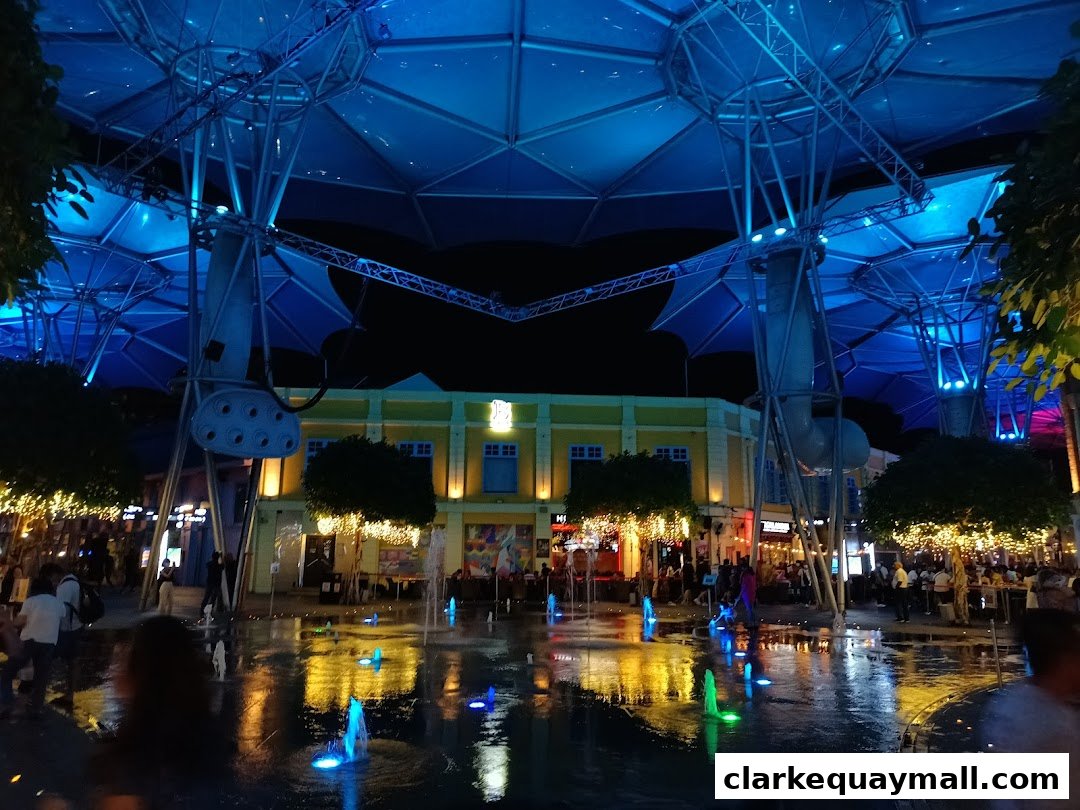 A lively night scene with illuminated fountains and people enjoying the atmosphere.