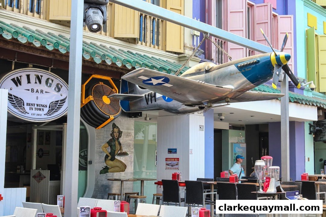 The exterior of Wings Bar & Grill features a vintage airplane model and a pin-up girl mural.
