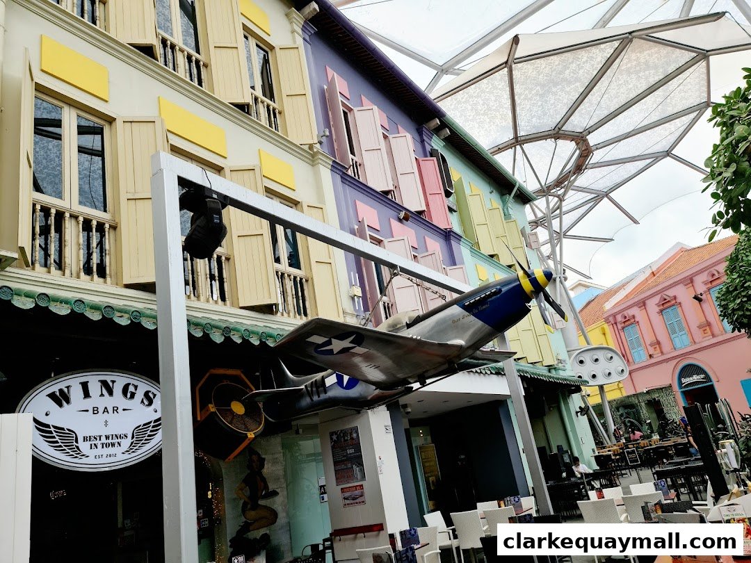 The exterior of Wings Bar & Grill features a vintage airplane model and colorful building facade.