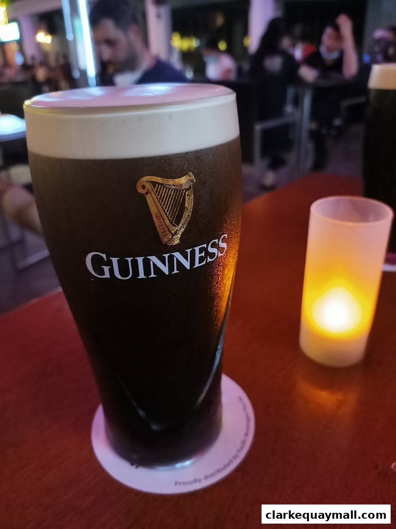 A close-up of a frothy Guinness beer with a candle lit in the background.