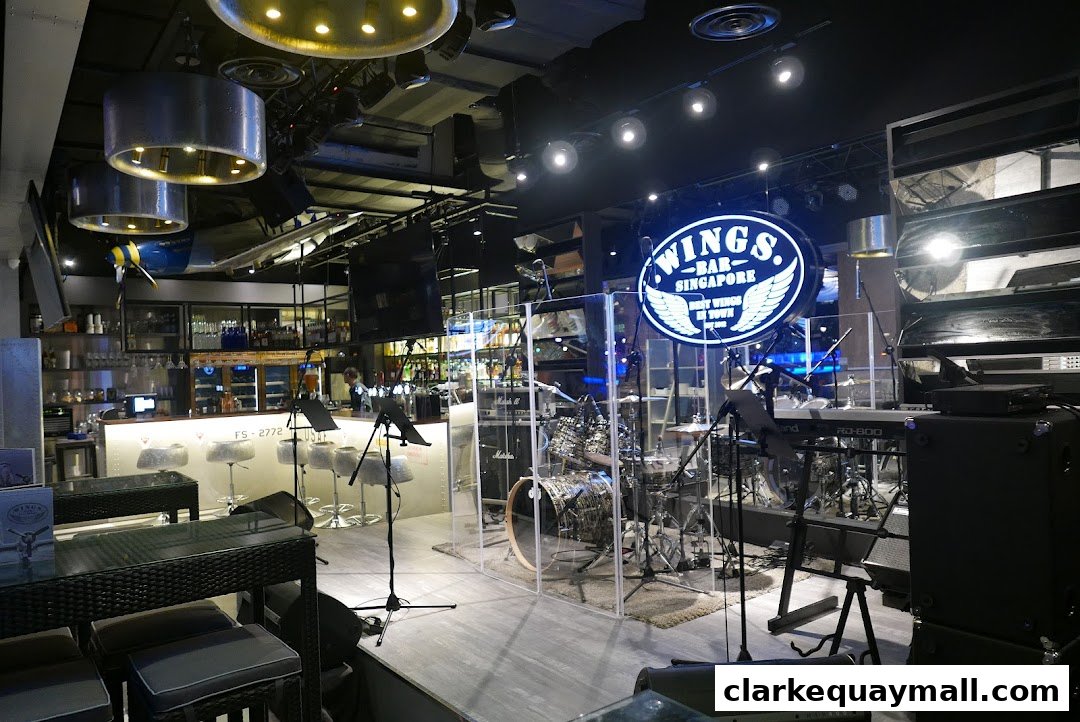 Interior of Wings Bar & Grill with a bar, stage, and musical instruments.