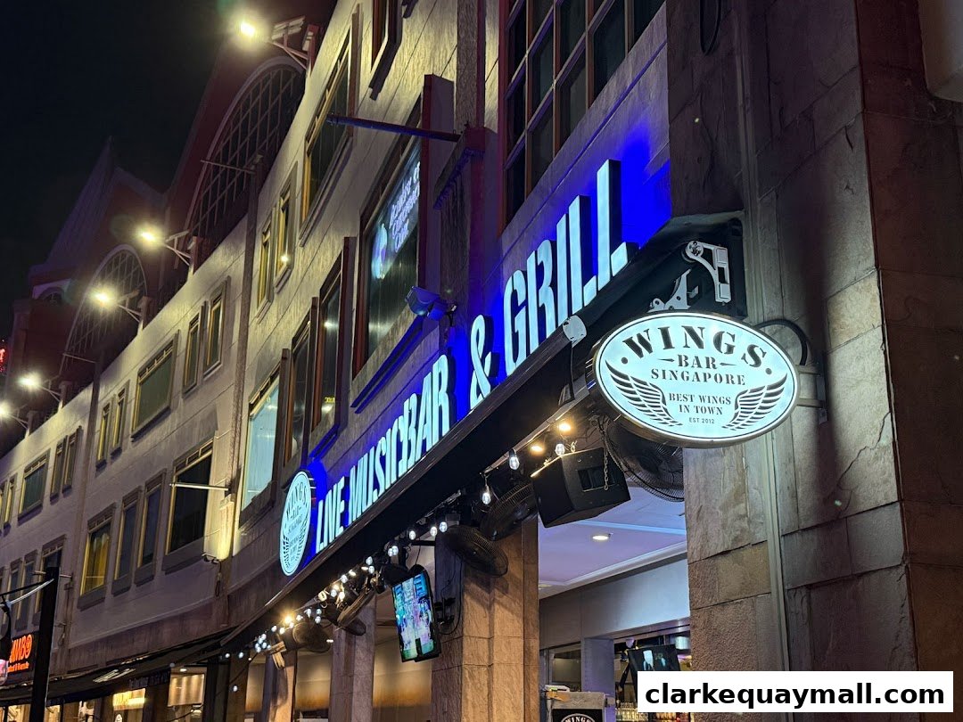 The exterior of Wings Bar & Grill at night, featuring illuminated signage and a welcoming entrance.