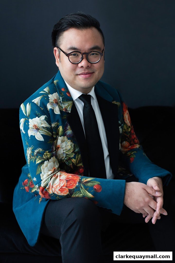 A man in a floral blazer and glasses poses for a portrait.