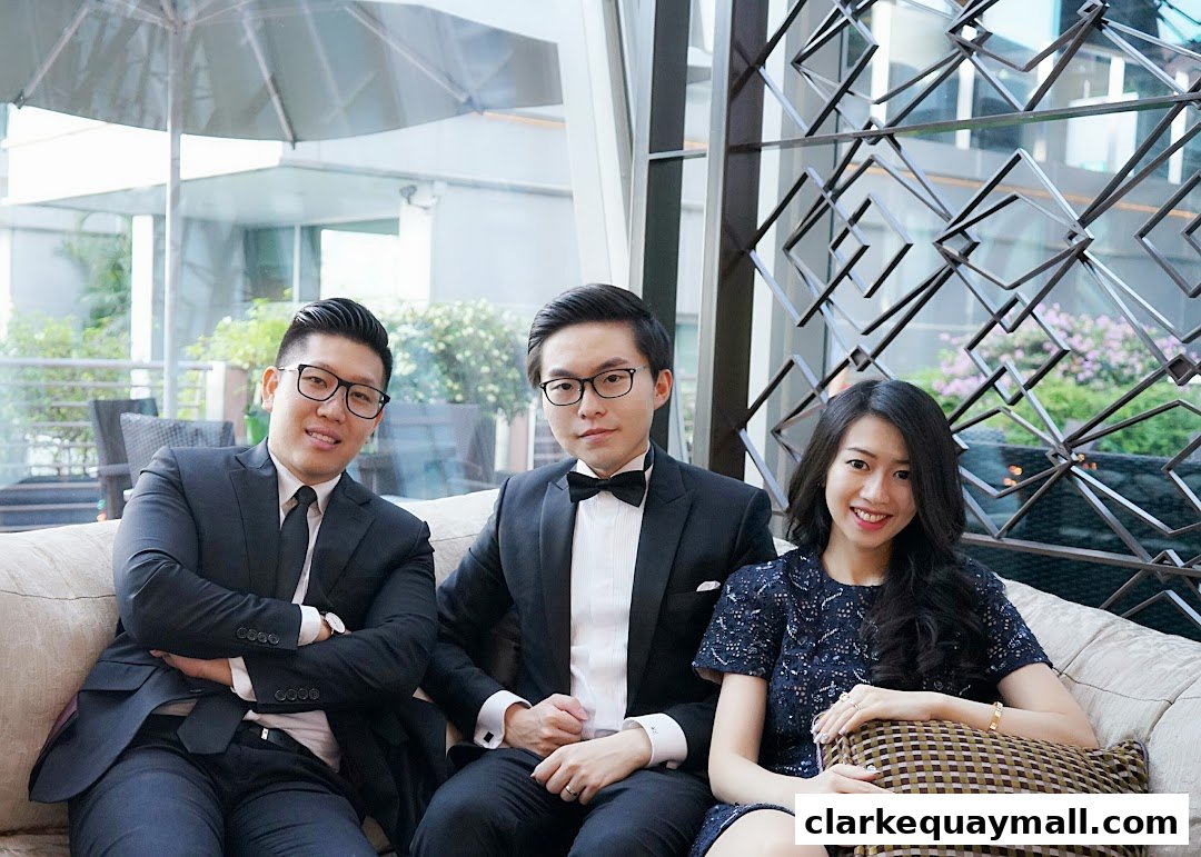 Three professionals in formal attire posing for a photo on a couch.