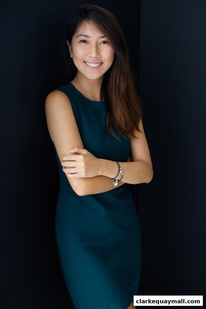 A professional portrait of a smiling woman in a teal dress against a dark background.