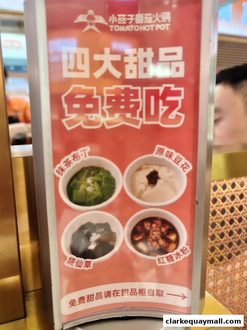 A sign advertising four free desserts at Tomato Hot Pot, featuring various sweet treats.