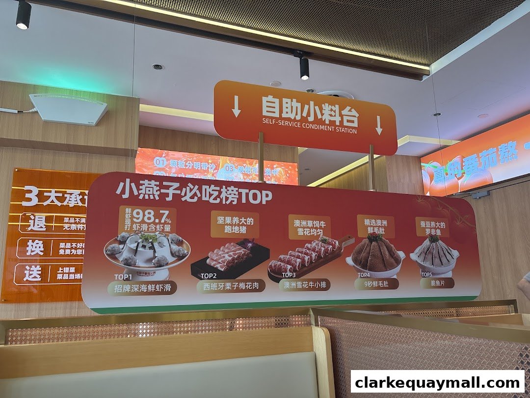 A sign displays the top 5 must-try dishes at XiaoYanZi Tomato Hot Pot, featuring various meats and seafood.