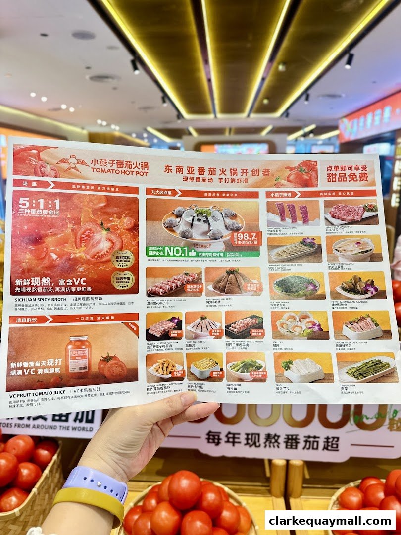 A person holds a menu for XiaoYanZi Tomato Hot Pot, showcasing various dishes and ingredients.