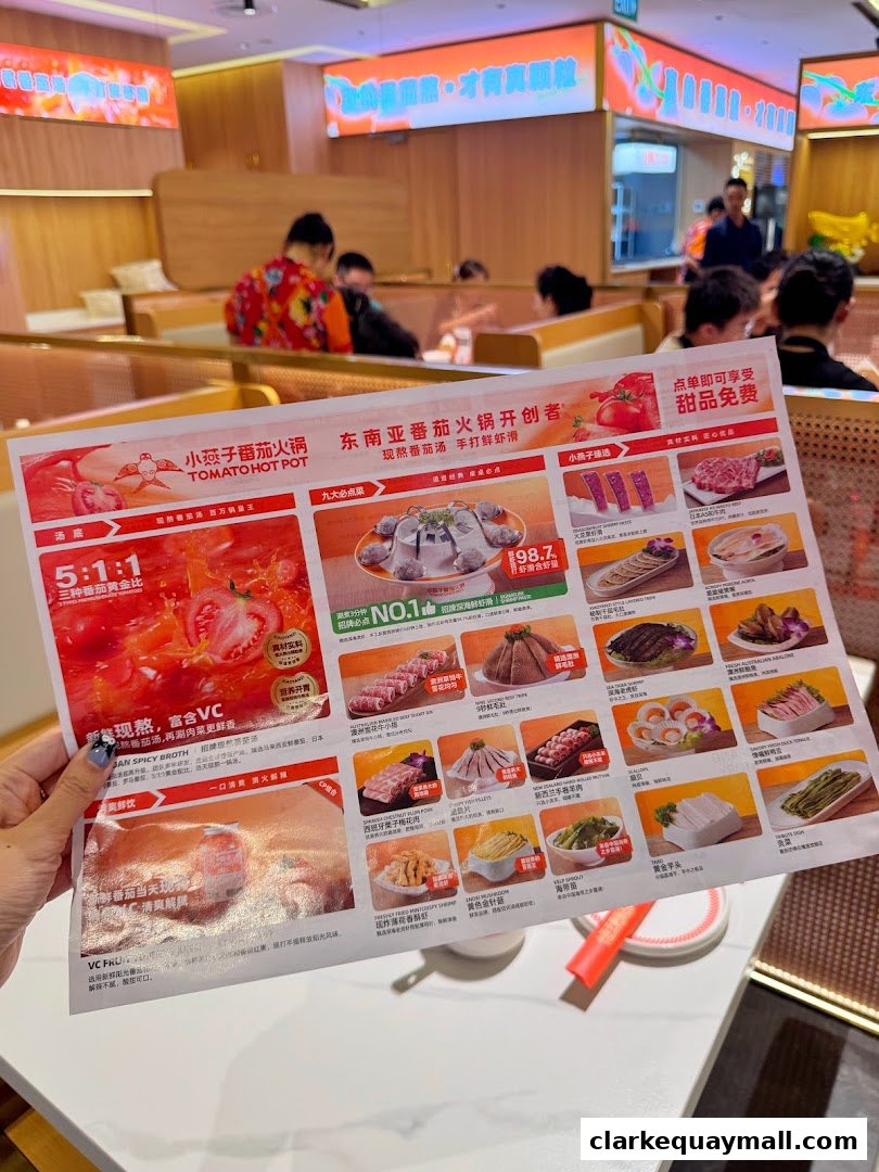 A person holds a menu for Tomato Hot Pot, showcasing various dishes and ingredients.