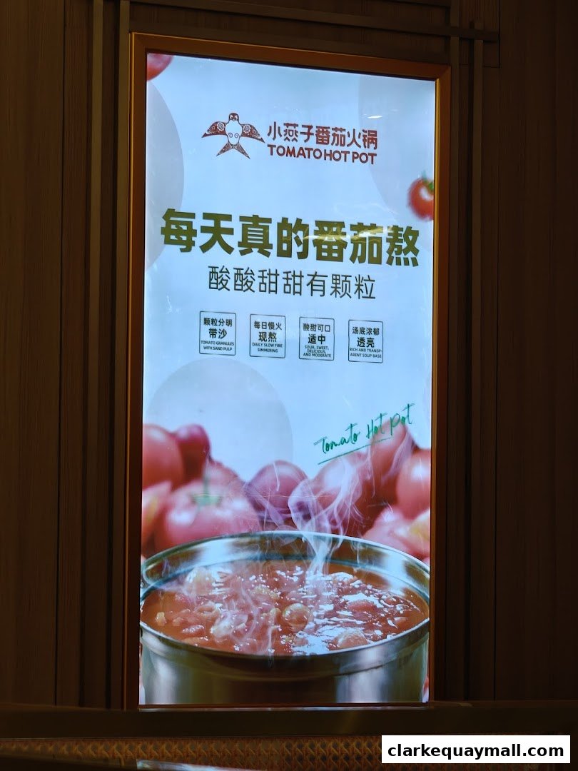 A glowing sign for XiaoYanZi Tomato Hot Pot, showcasing a steaming bowl of tomato soup.